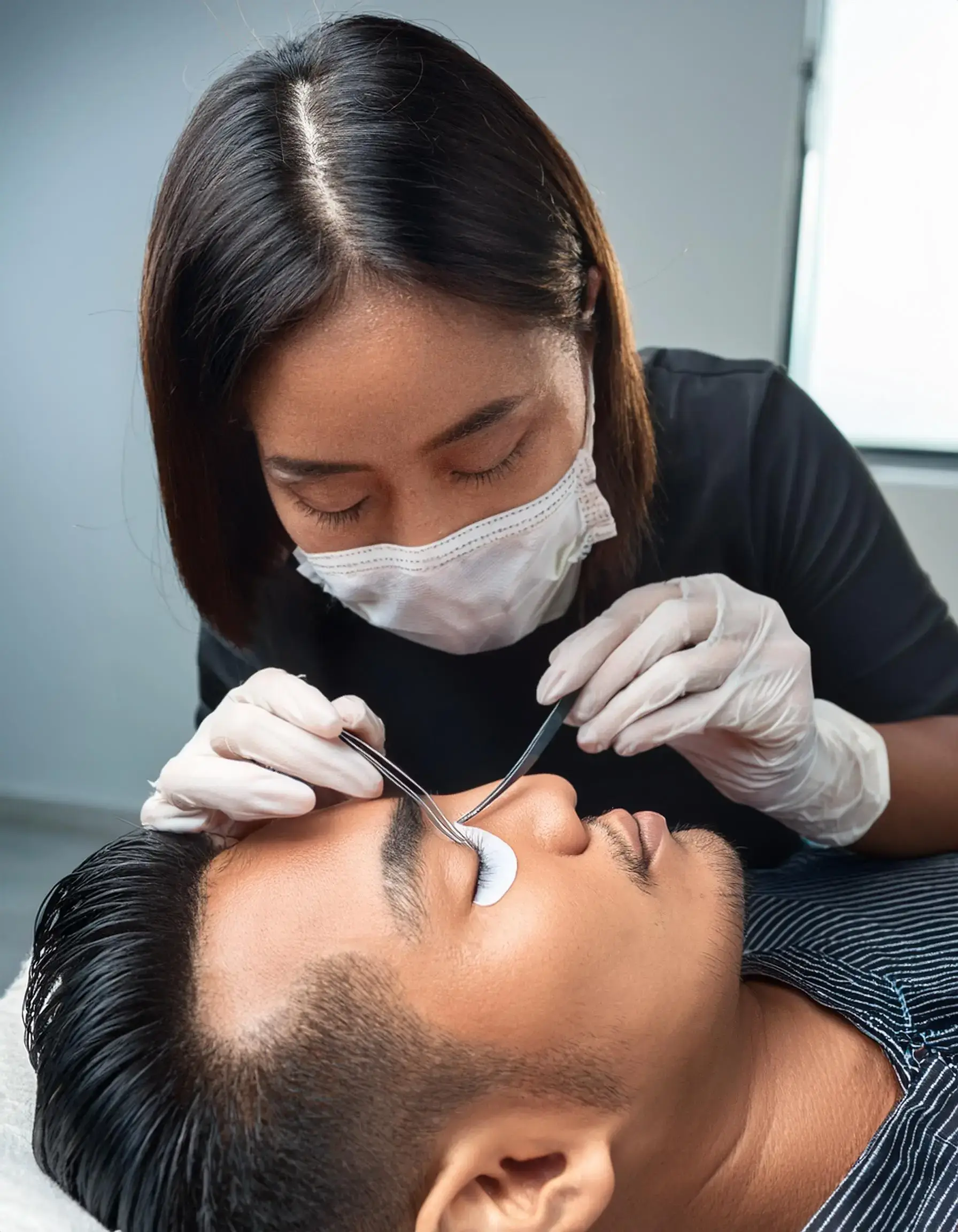 Enhance Your Look with Male Eyelash Extensions in Toronto - Firefly A professional lash artist carefully applying individual lash extensions to a male clients 3